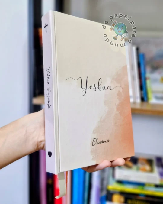 Bíblia reformada segurada na mão, com capa bege, a palavra Yeshua em manuscrito e o nome da cliente abaixo