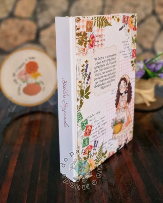 Bíblia reformada com capa em colagem de elementos botânicos, versículo e ilustração de uma mulher em oração