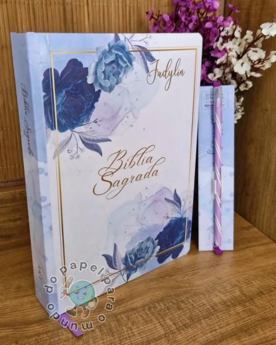 Bíblia reformada com capa branca, buquê de flores azuis e nome da cliente em letras douradas, com caderno pequeno ao lado